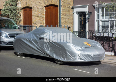 Porsche 911 car under a car cover parked on a road in Notting Hill, London, UK Stock Photo