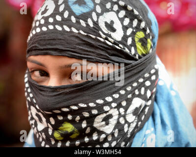 Young Indian Rajasthani woman with romantic eyes covers her hair and lower face with a secular dust veil. Stock Photo