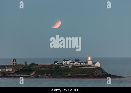 Roches Point, Cork, Ireland. 16th July, 2019. On the 50th anniversary of the Apollo Eleven mission a partial eclipse of a full moon takes place over the Roches Point Lighthouse in Cork Harbour, Ireland. Credit: David Creedon/Alamy Live News Stock Photo