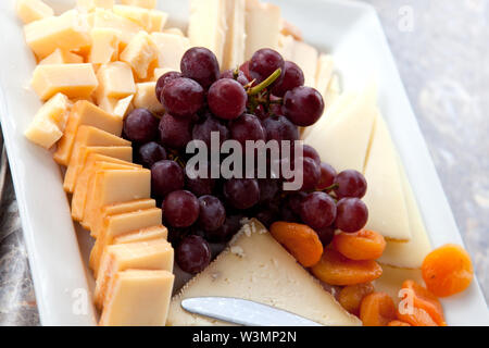 A platter of swiss, cheddar cheese with grapes and apricots Stock Photo