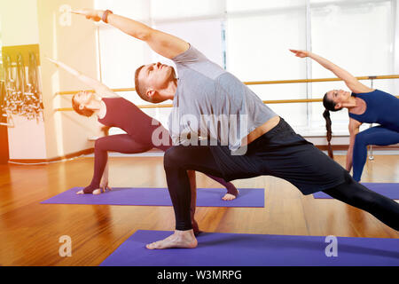 Fitness, yoga and healthy lifestyle concept - a group of people who do exercises for stretching and meditating in various yoga poses. Stock Photo