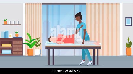 man lying on massage bed african american masseuse therapist doing healing treatment massaging injured patient manual physical therapy concept modern Stock Vector