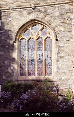 Stained glass window with tracery carving on the exterior stone walls of a church. Stock Photo