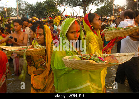 Women with offerings on the four day long Chhath Puja (worship) also known as Surya Shashti, dedicated to the Sun God, Surya. Rituals of the puja includes bathing in the holy waters of the Ganges river, prayer and offerings to the God. The festival is remarkable for its display of colourful costumes, music and extravagant rituals. Kolkata, India. November 4, 2008. Stock Photo