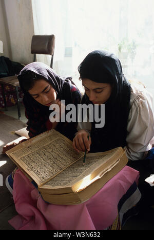 Lina (with white dress and black head scraf), 18, recites the Koran with a girl and two young women, seated on the floor in her home in the Khairkhana neighbourhood in Kabul, the capital. Lina completed the third grade before she was forced to stop school. Determined to continue her education, she asked her brother, a university student, to help her study. She now takes tailoring and embroidery, as well as literacy and other classes, at an educational centre run by the UNICEF-assisted General Work and Development Association (GWA), a local NGO. The Association offers a non-formal education pro Stock Photo