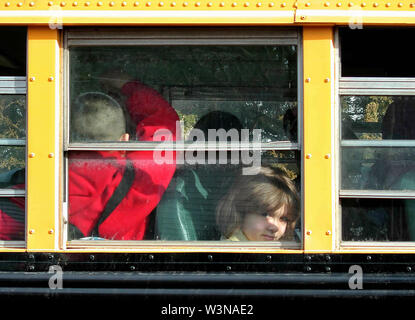 Middletown, CT USA. Mar 2015. A little girl inside a school bus shying away from the camera at a residential drop off place. Stock Photo