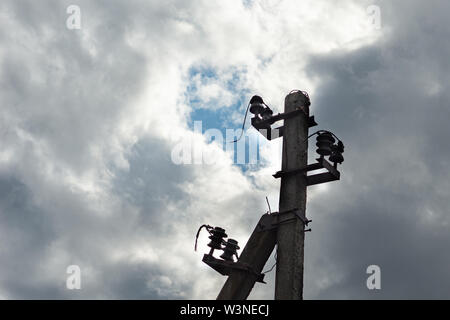 Electrical utility pole made of concrete, cut wires, corroded metal parts against the background of overcast sky. Small blue clearance Stock Photo