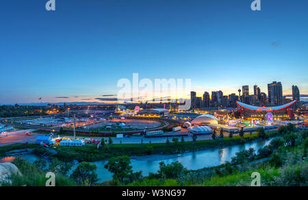 CALGARY, CANADA - JULY 14, 2019: Panorama of golden sunset over the Calgary Stampede fairgrounds surrounded by the Bow River with the city's urban sky Stock Photo