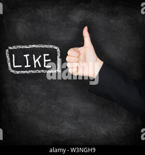 Like - likes thumbs up on chalkboard. LIKE written on blackboard with hand giving thumbs up hand sign gesture. Black blackboard texture background icon. Stock Photo