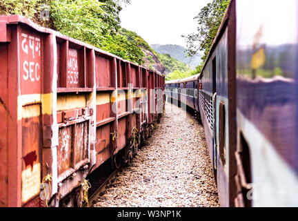 Goods Train of SEC Indian Railways giving pass to holiday special passenger train amidst greenery of the Western Ghats. Stock Photo