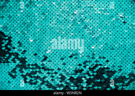 Abstract festive sparkling background. Round iridescent turquoise sequins on fabric. Stock Photo