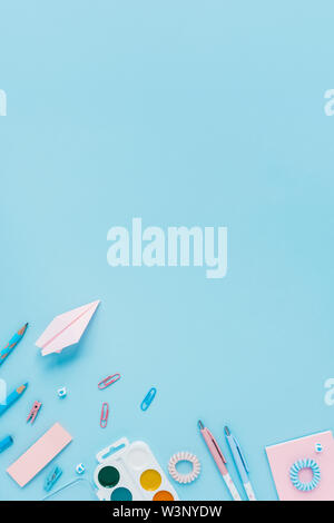 Pens, pencils, watercolor paints, paper clips, clothespins on a blue background. Place for your text. Stock Photo