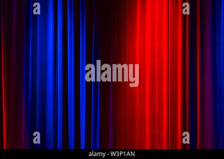 Front view of a closed vintage style velvet theater curtain illuminated by a red and a blue spotlight Stock Photo