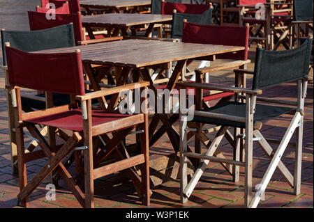 A cafe setting outside with canvas, wooden tables and chairs. Stock Photo