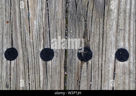 Aged wooden sleepers are on the ground, they have fine gravel in their grooves, there are circular burn marks on them. Stock Photo