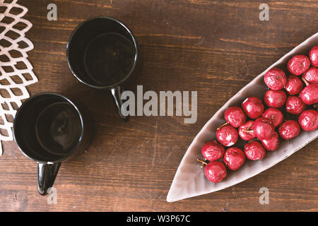 Photo of Table with two empty cups and artificial berries in a plate Stock Photo