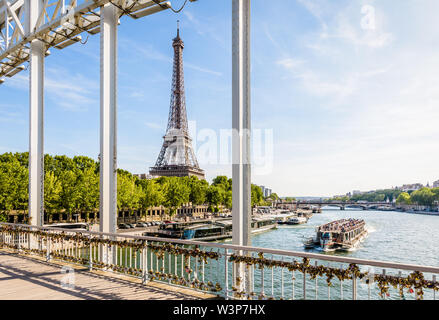 The Eiffel tower in Paris, France, seen from the Debilly footbridge on a sunny summer afternoon with a tourist river boat cruising on the river Seine Stock Photo