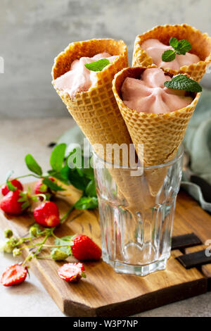 Strawberry of ice cream scoops in cones on a light stone or slate table. Stock Photo