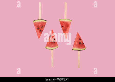 Juicy red ripe fresh watermelon popsicles on pink background Stock Photo