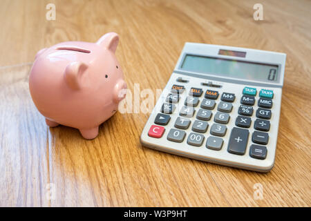 Cute Piggybank and calculator on wooden background Stock Photo