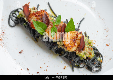 close up of tagliolini squid black ink pasta scallop seafood sauce, bottarga roe mullet eggs, zucchini vegetable fresh cream, garlic, basil, italian f Stock Photo