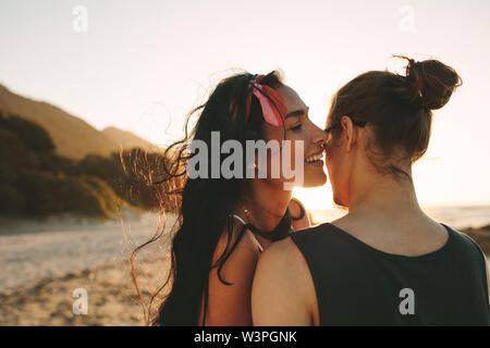 Woman whispering loving words in ear on her boyfriend. Beautiful couple spending time together on their summer vacation. Stock Photo