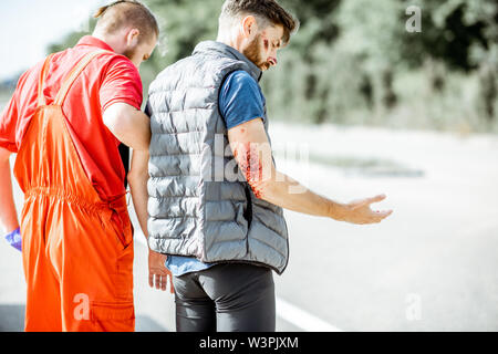 Medic In Uniform Helping Injured Man To Walk, Applying First Aid After ...