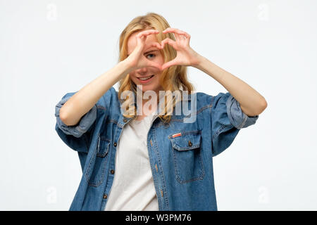 blonde woman smiling in love showing heart symbol and shape with hands Stock Photo