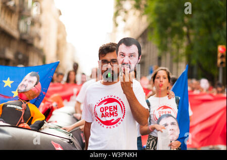 Barcelona, spain- 17 july 2019: young open arms activist march holding rubber dinghy and italian minister Salvini mask against immigration policies an Stock Photo