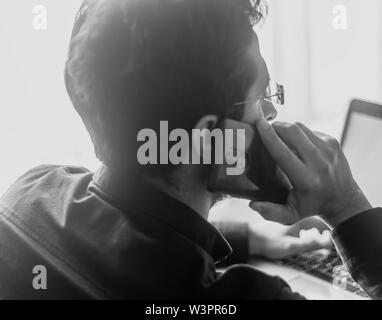 Man attending phone call with laptop in front. busy businessman background Stock Photo