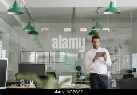 Focused young businessman working on a tablet in an office Stock Photo