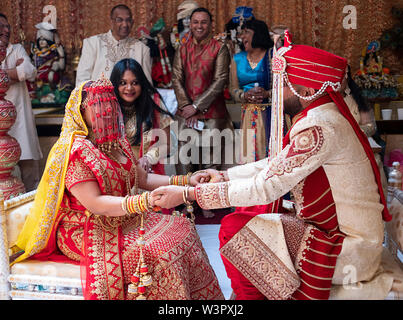 A bride and groom hold hands during a traditional Hindu wedding ceremony in a temple in Ozone Park, Queens, New York City. Stock Photo