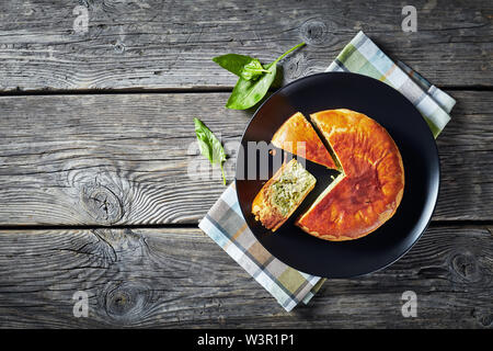 Green Bean spinach and blue cheese pie on a black plate on a rustic wooden table, horizontal view from above, flat lay Stock Photo