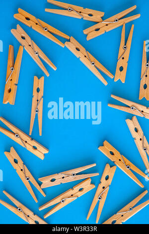 Wooden yellow clothespins are scattered on a cyan-blue background. Frame of clothespins. View from above. Copy space. Flat lay. The concept is natural Stock Photo