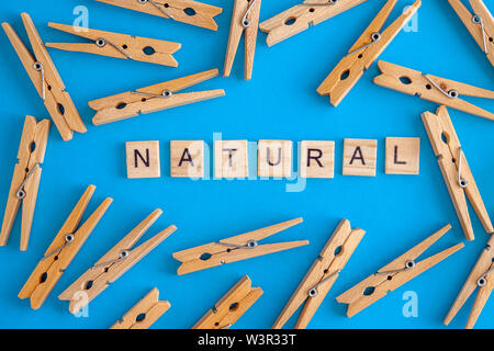 Wooden clothespins are scattered on a white and blue background with the words eco and natural. View from above. Copy space. Flat lay. The concept is Stock Photo
