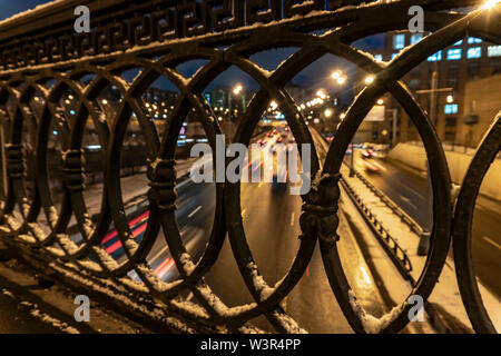 shot of the night traffic made through a cast-iron fence Stock Photo