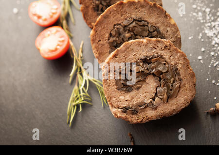 Tasty Meatloaf with mushrooms on black background Stock Photo