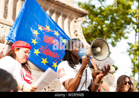 Barcelona, spain- 17 july 2019:  young african woman reading manifesto against far right eith european union flag with blood stains on it in daylight Stock Photo