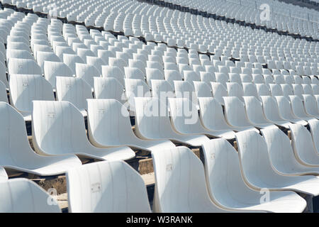 Rows of empty white plastic seats at the tribune in an open sports stadium Stock Photo