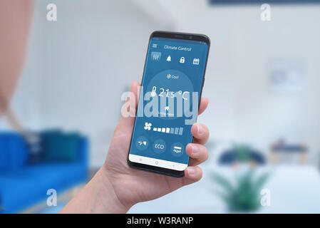 Modern climate control app interface on a smartphone in hand. Concept of simple temperature control and auto heating. Stock Photo
