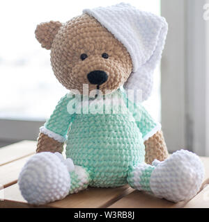 Handmade amigurumi teddy bear on wooden table. Stock Photo