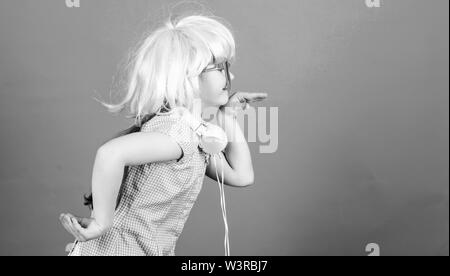 Inspired by music. Little kid listening music. Cute kid with headphones blue background. Small girl headphones pink wig dancing. Child using technology for fun. Modern headphones. Energy motion dance. Stock Photo