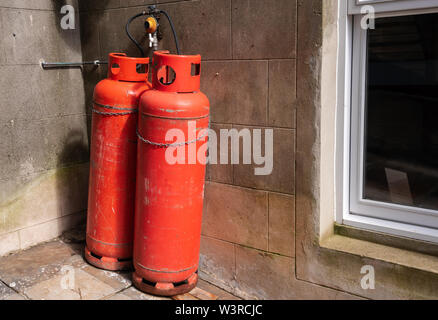 Two Red Propane Cylinder on the exterior of an old house Stock Photo