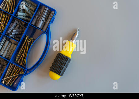 Tool box with screws, various types of parts and screwdrivers On a gray background. Do it yourself. Repair concept. Flat lay. Copy space. Stock Photo