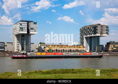 container ship in front of the Crane Houses at the Rheinau harbour, Cologne, Germany.  Containerschiff vor den Kranhaeusern im Rheinauhafen, Koeln, De Stock Photo