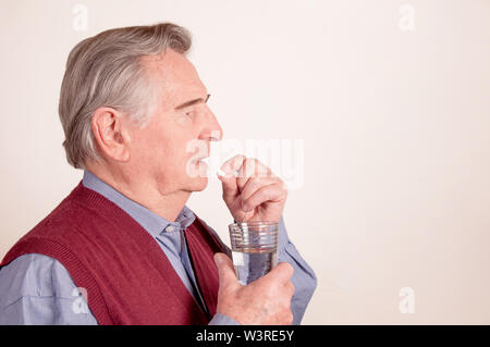 Senior takes pill with glas of water Stock Photo