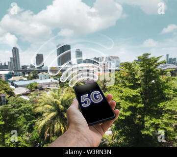 Man holding phone with 5G mobile network logo on screen. Fifth generation wireless network . technology . Stock Photo