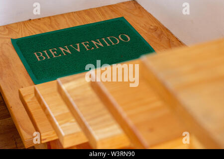 Welcome mat on wood stairs in spanish Stock Photo