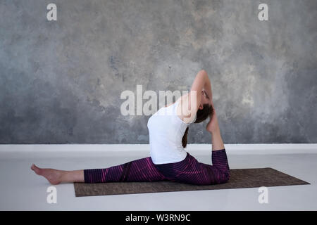 woman working out, doing yoga or pilates exercise. Monkey god, hanumanasana. Stock Photo