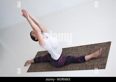 European mature woman practicing yoga doing Hanumanasana Stock Photo